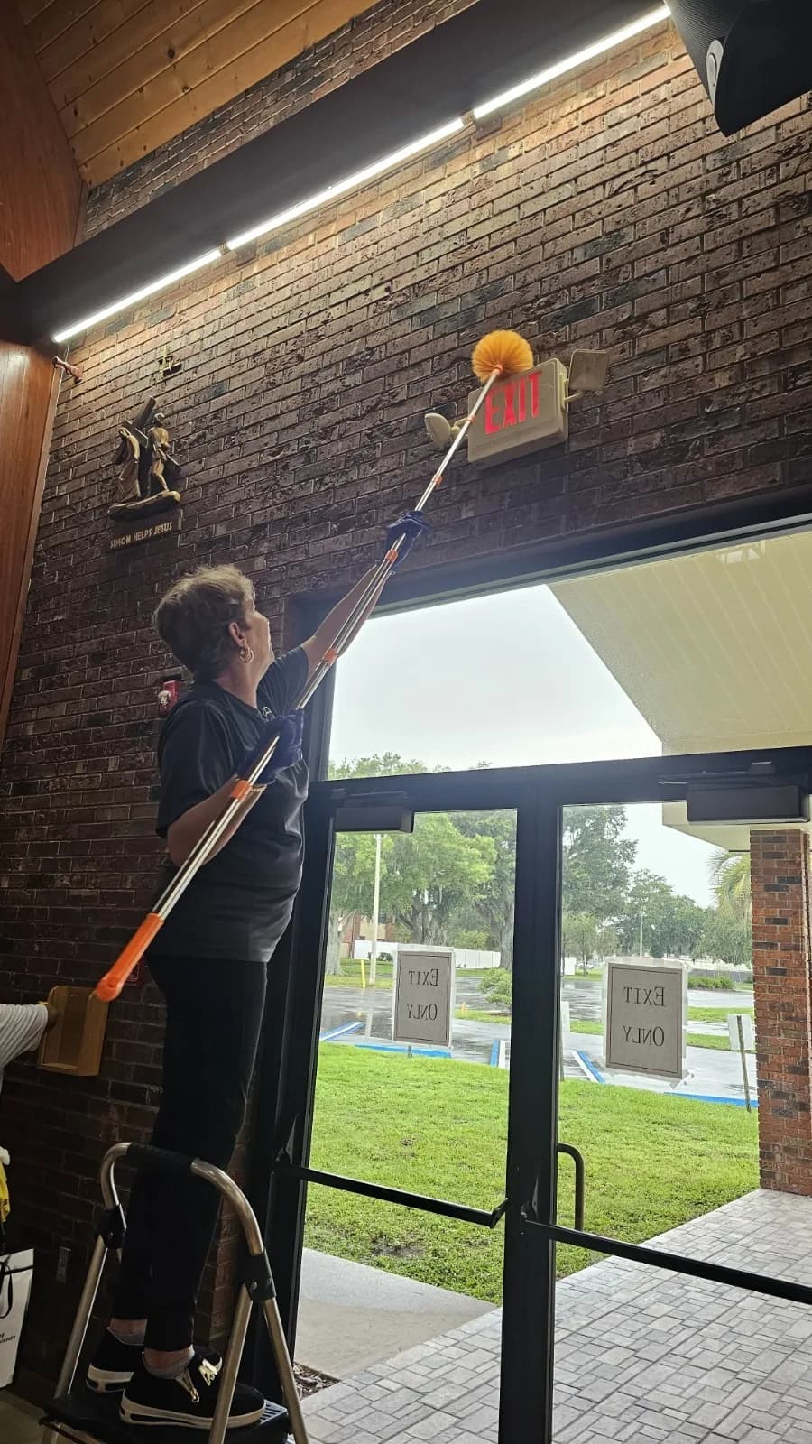 Empire crew member cleaning high church windows from a ladder