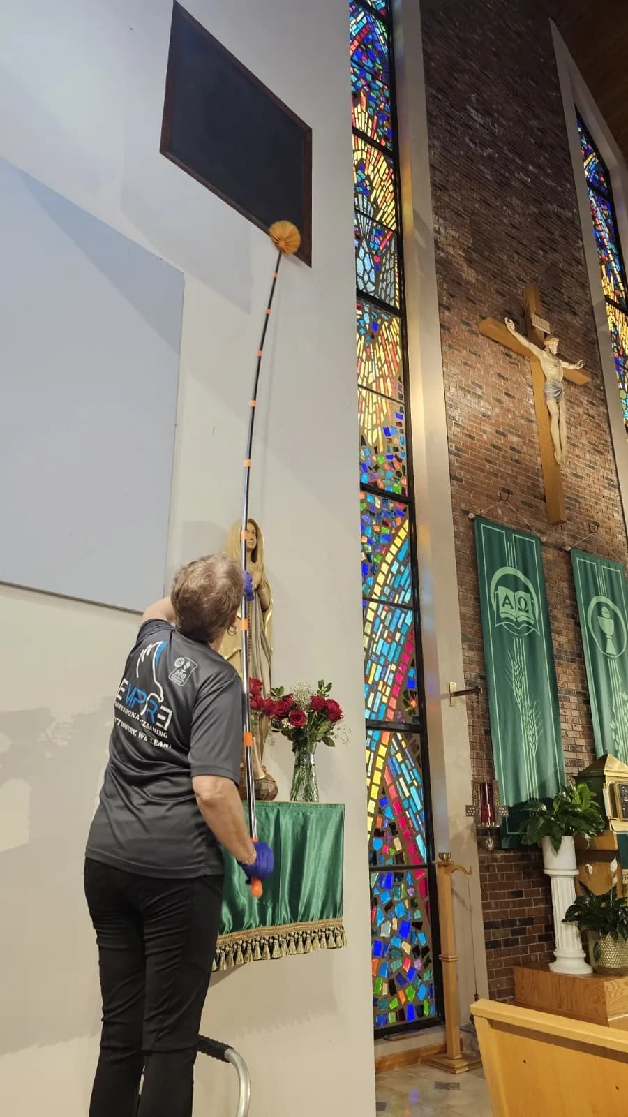 Empire crew member cleaning tall stained glass windows at a Central Florida church